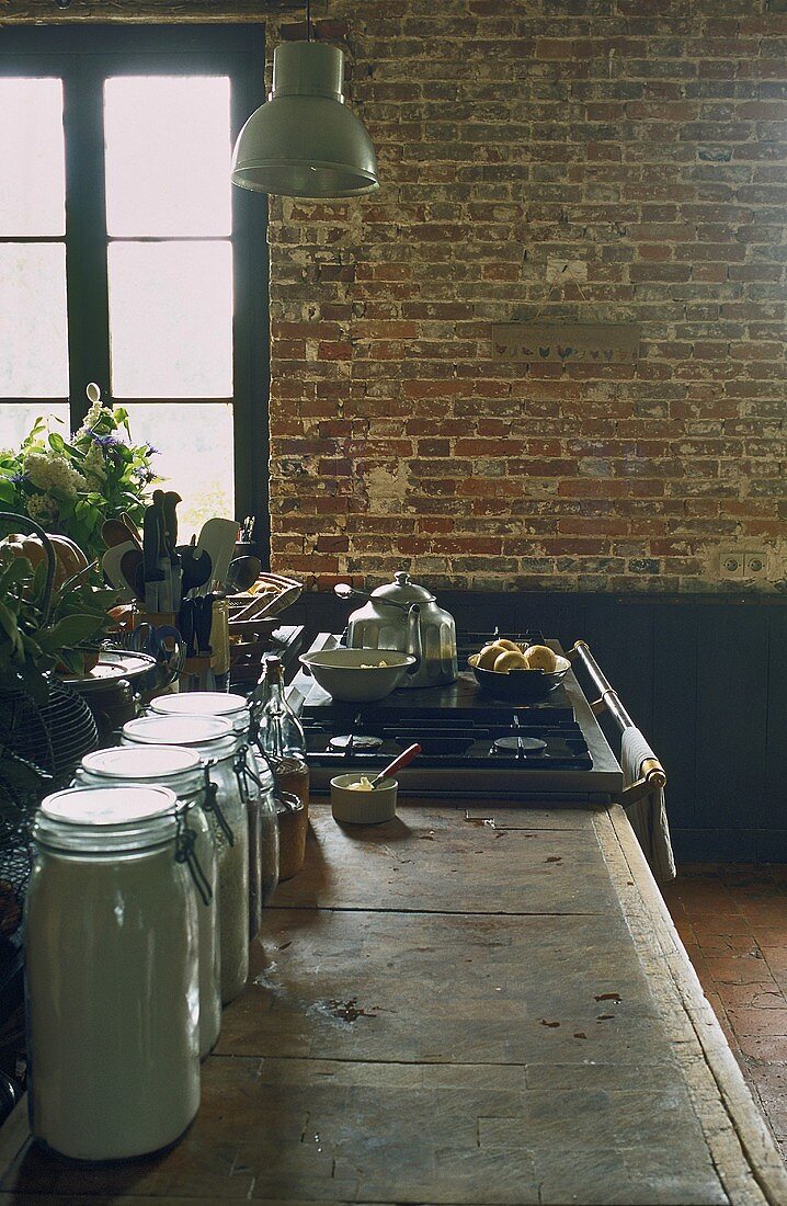 A rustic dining room with a brick wall and a kitchen counter with storage jars