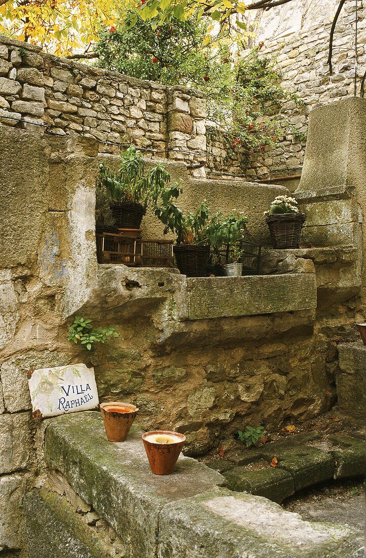 Mediterraner Platz mit Natursteinmauern und Pflanzen auf Steinablagen