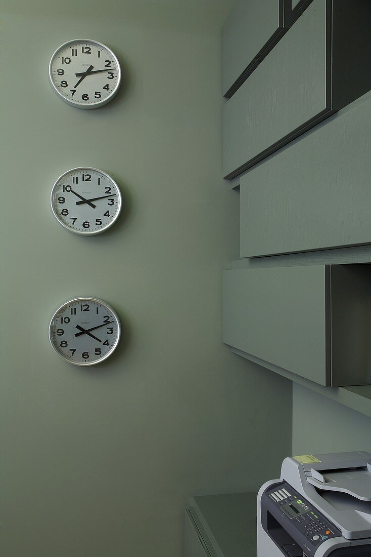 Clocks on a grey wall showing different times