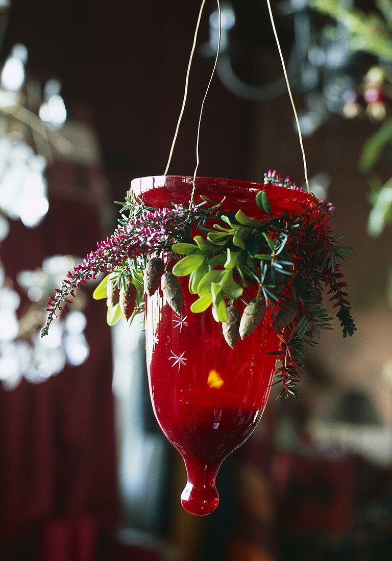 Gehängtes Windlicht im roten Glasbehälter mit Weihnachtsdeko
