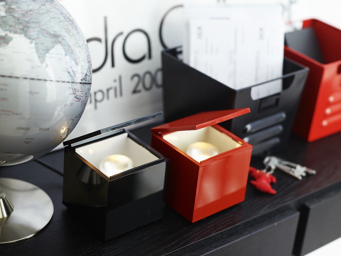 Tea lights with red and black packaging next to a globe on a black surface