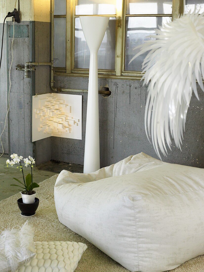 White pouf pillow and white floor lamp