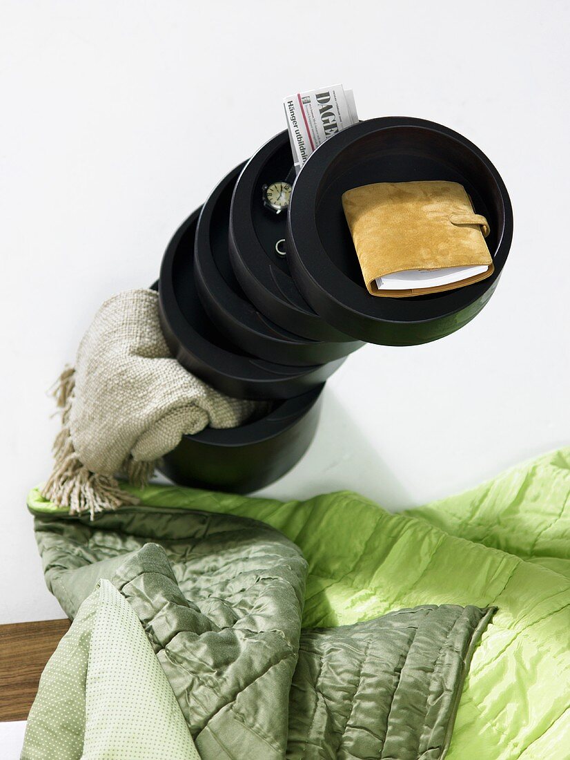 Stacked dark colored wooden bowl and green quilt