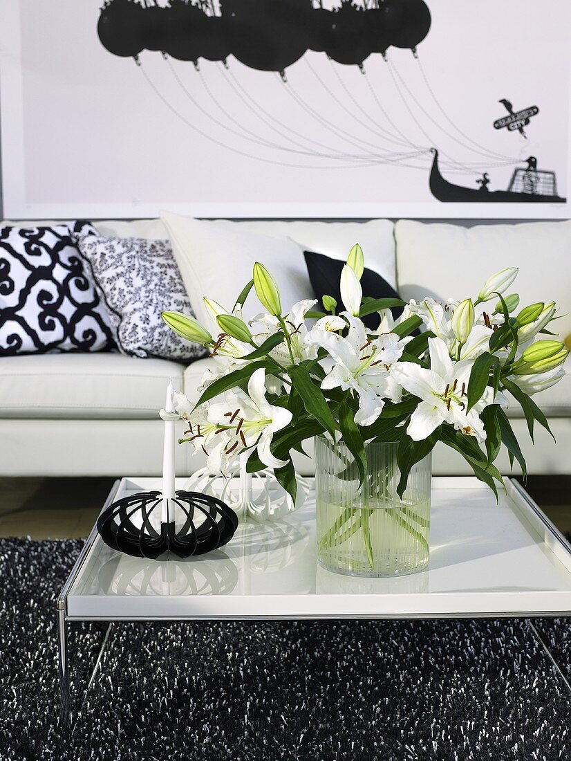 Bouquet of white lilies on a modern coffee table in front of a sofa