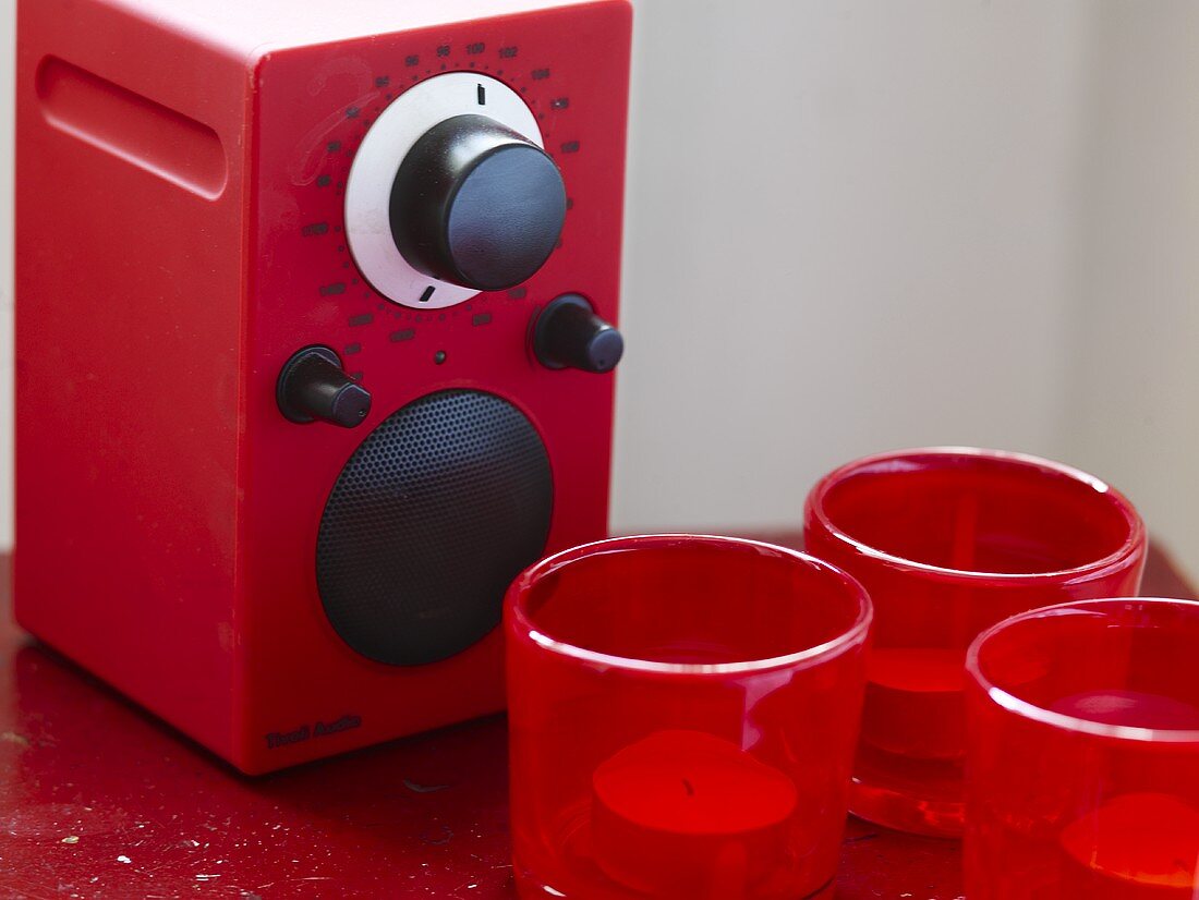 Radio with red cover and tea lights in red glass