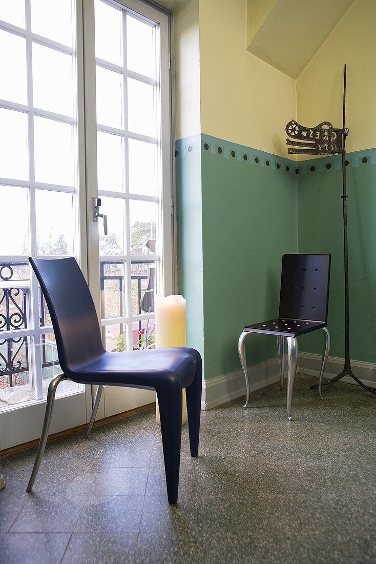 Stühle mit schwarzer Kunststoffschale im Designerstil vor Balkontür und bemalter Zimmerecke