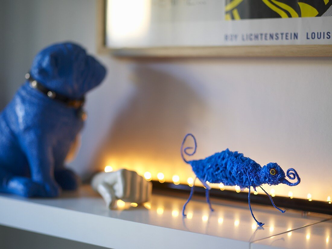 Blaue Tierfigur auf beleuchteter weisser Ablage