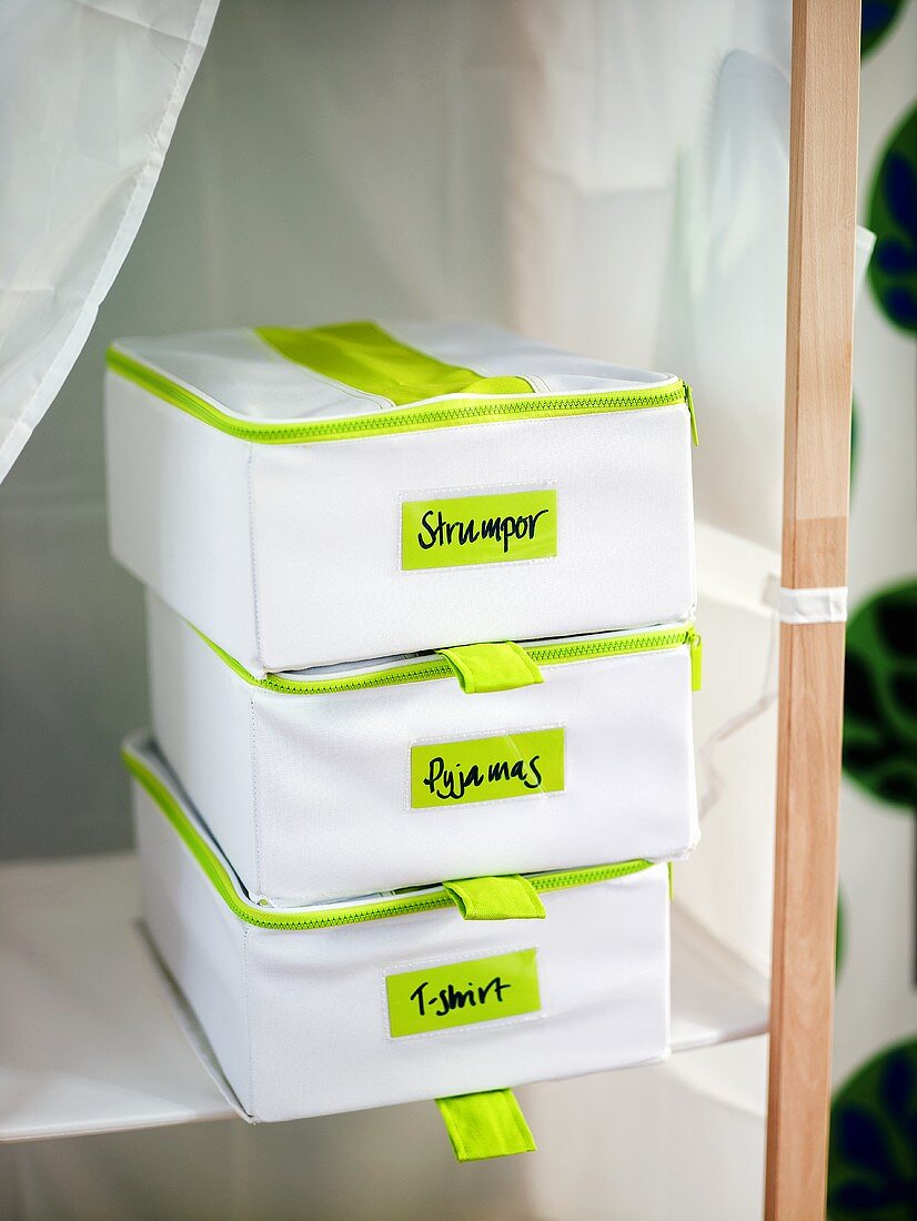 Labelled plastic boxes on a shelf covered in white fabric