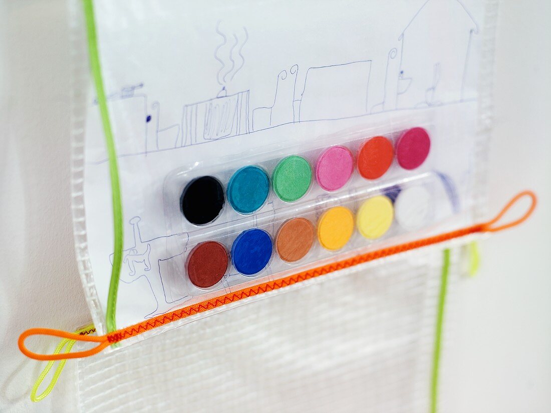 Zeichnung und bunte Wasserfarbentöpfe in Kunststoff eingeschweisst
