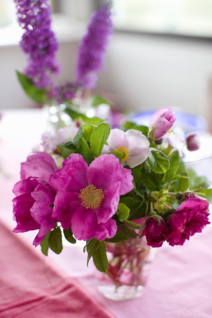 Pinkfarbener Blumenstrauss in Glasvase auf rosa Untergrund