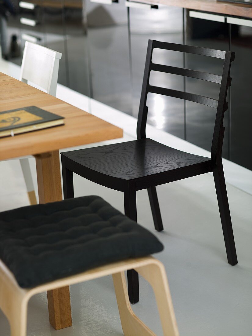 Schwarzer Küchenstuhl und heller Hocker aus Holz mit Polster