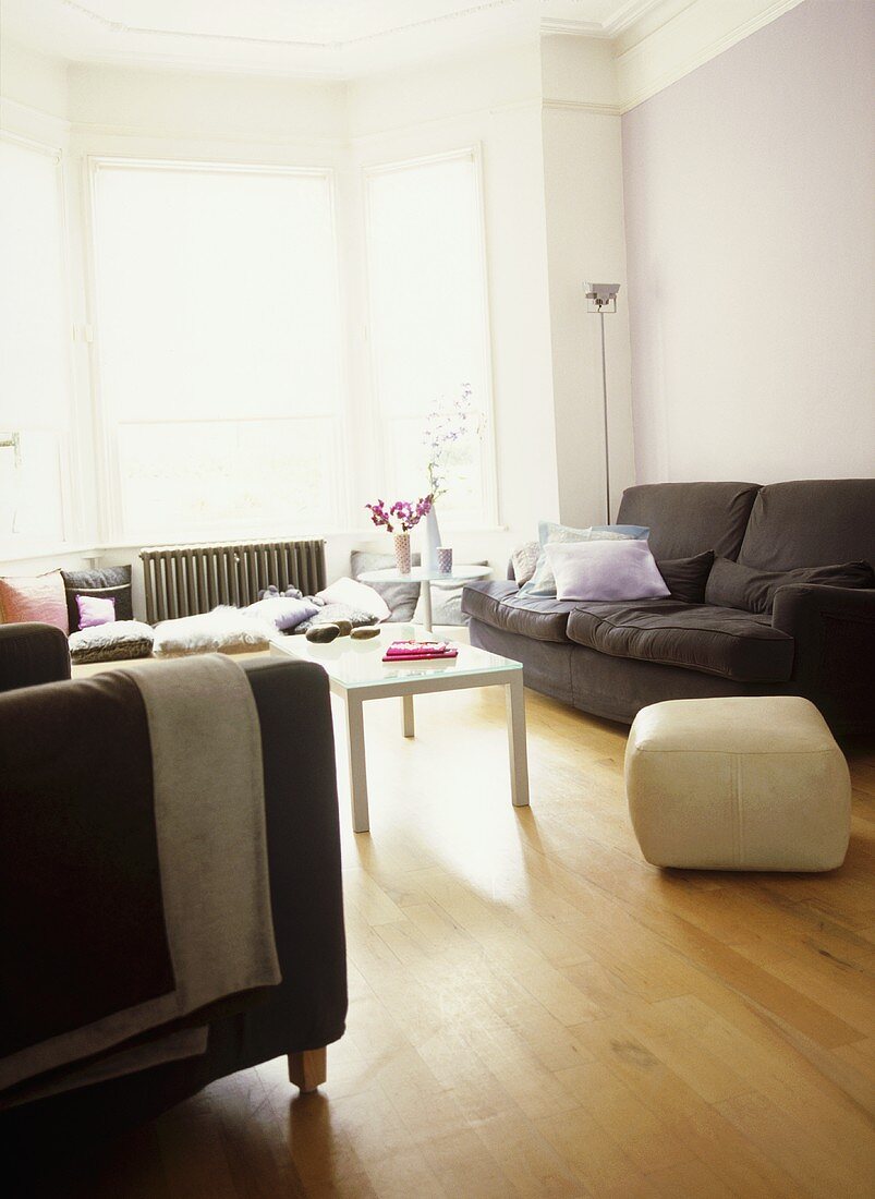 A modern lilac sitting room with upholstered sofa, armchair, white coffee table, wood floor