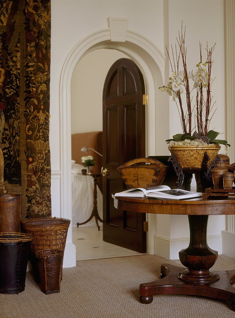 Flur in einer Villa mit antikem Beistelltisch aus Holz und offener Rundbogentür mit Blick auf Bett