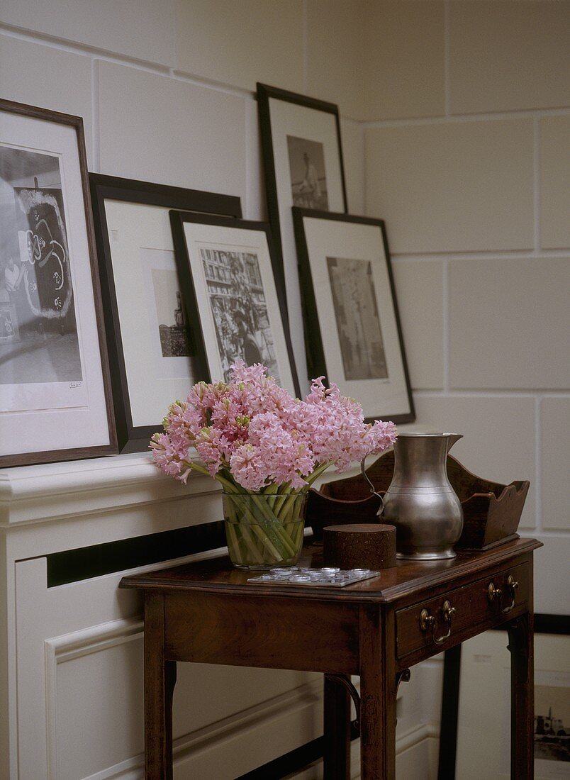 Zimmerecke mit antikem Wandtisch und Schublade mit gerahmten Bildern auf Ablage vor Steinwand