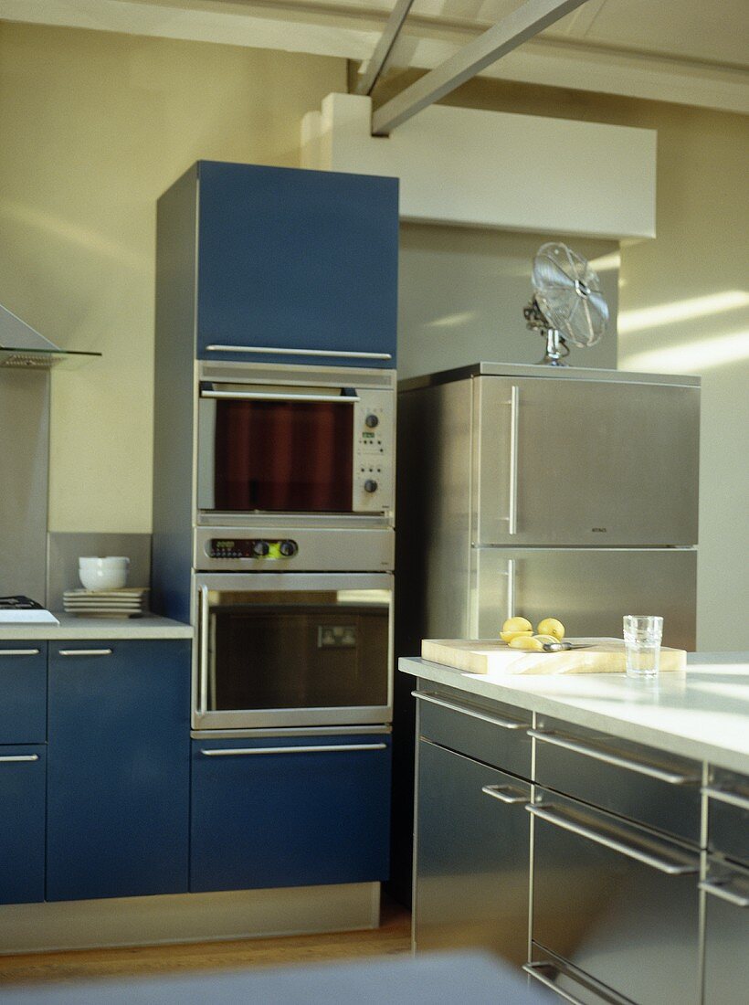 Offene Küche mit blauen Schrankfronten und Edelstahlfronten