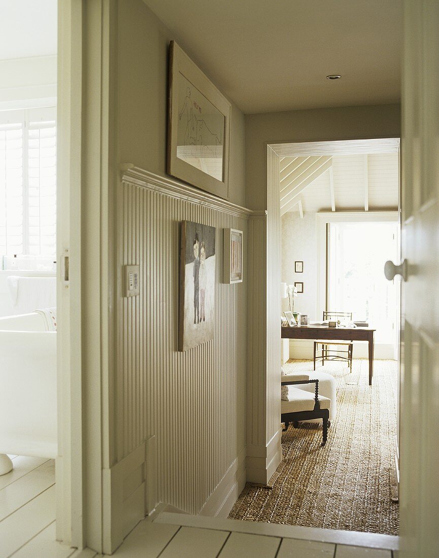 A country hallway, painted floorboards, view through open door to home office study room, wall panelling,