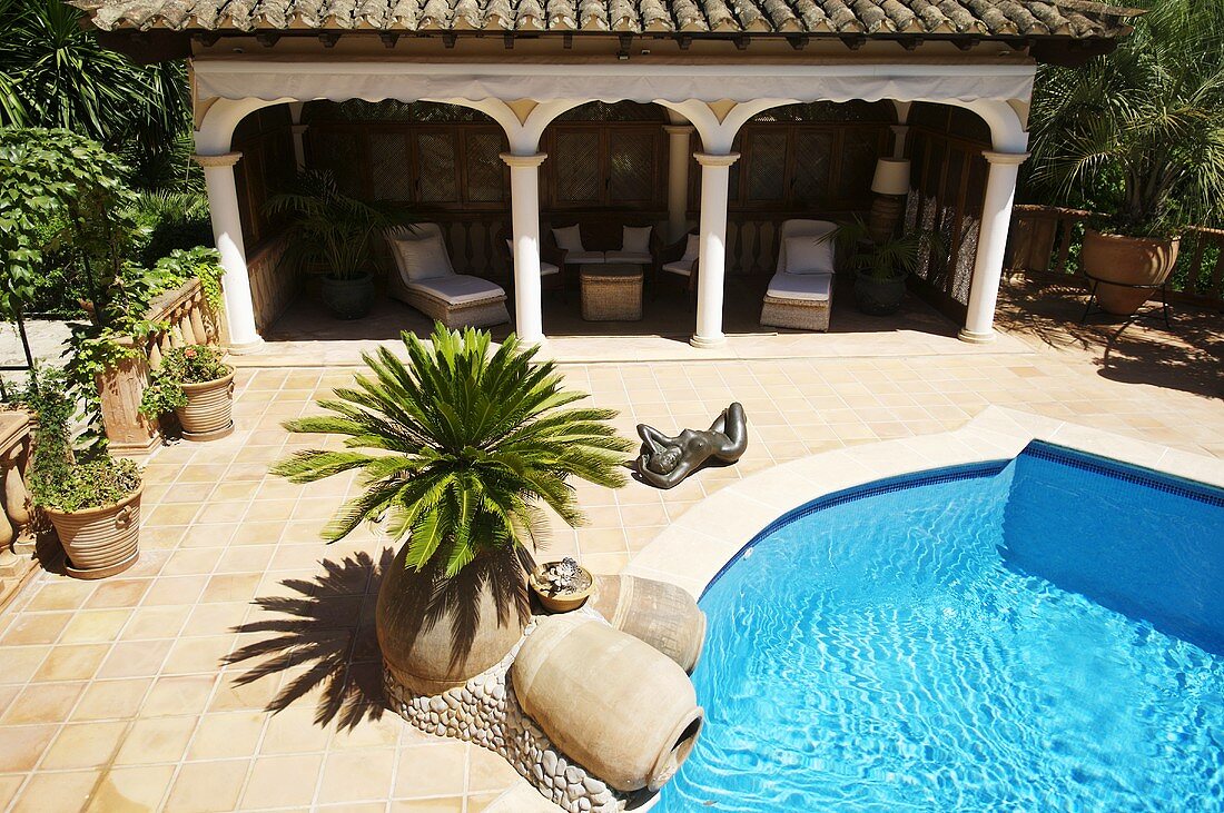 Blick auf Schwimmbad und elegante Loggia mit antiken Säulen und Terrassenmöbeln
