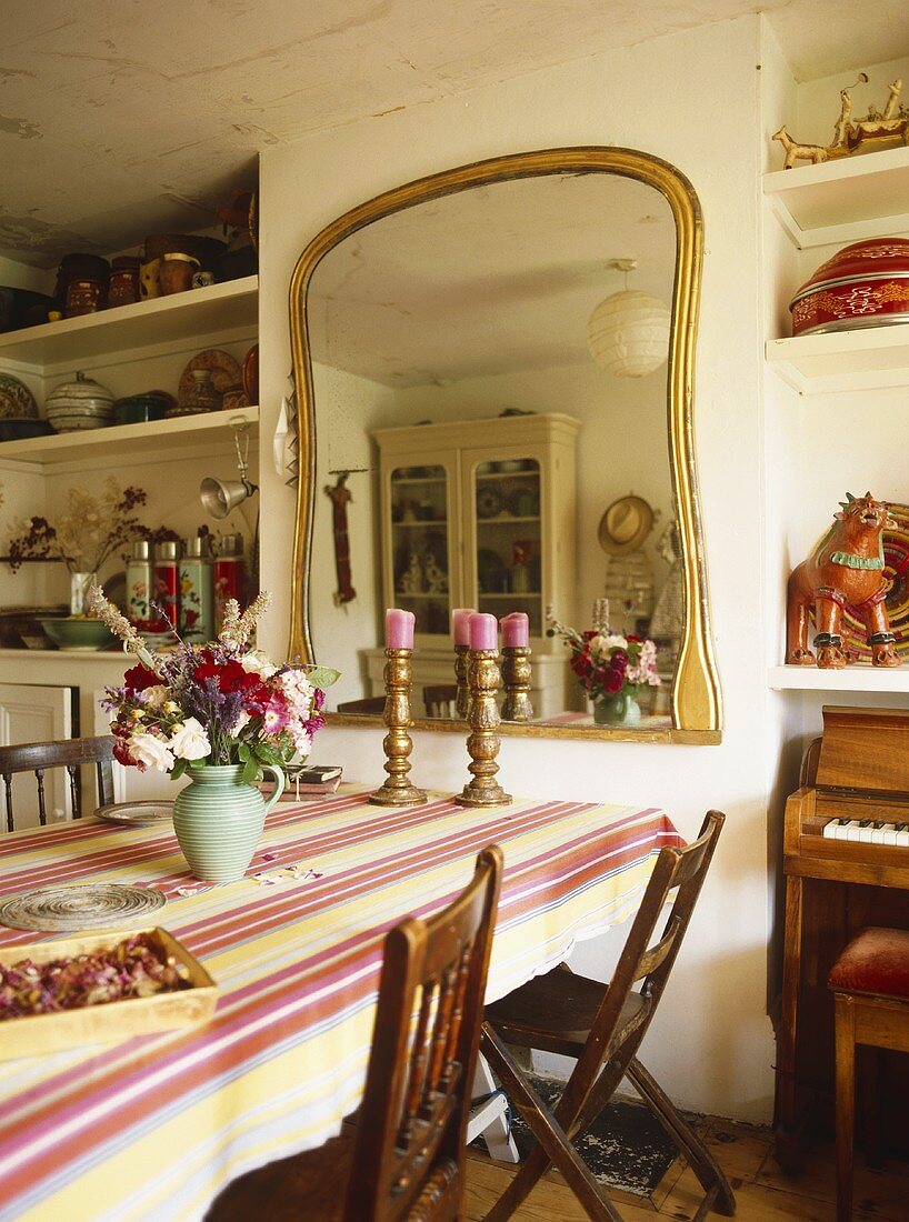 Esszimmer im Landhausstil - Blumen und Leuchter auf Tisch vor Spiegel mit Goldrahmen