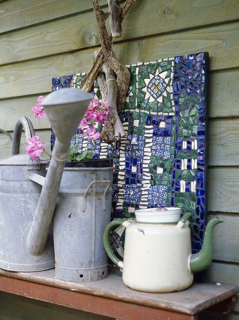 Enamel teapot and watering can on wooden table