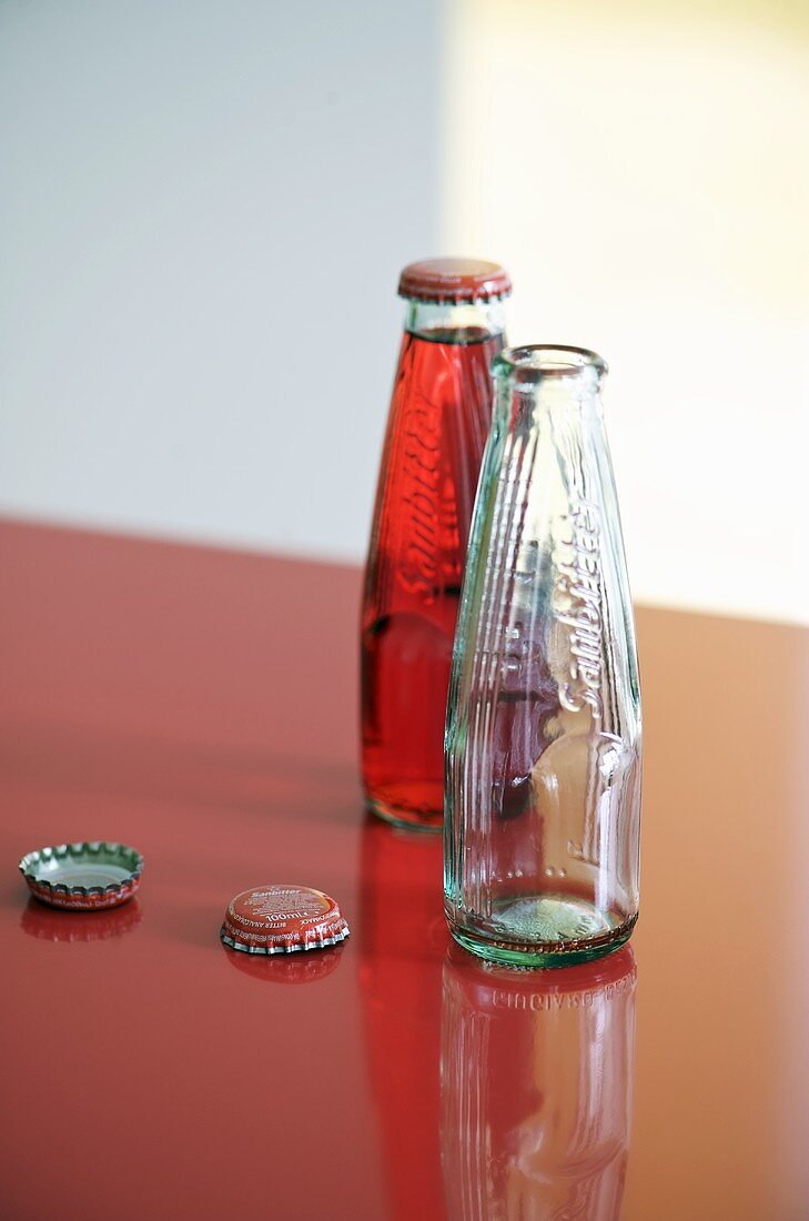 Leere und gefüllte Flasche auf roter Arbeitsplatte