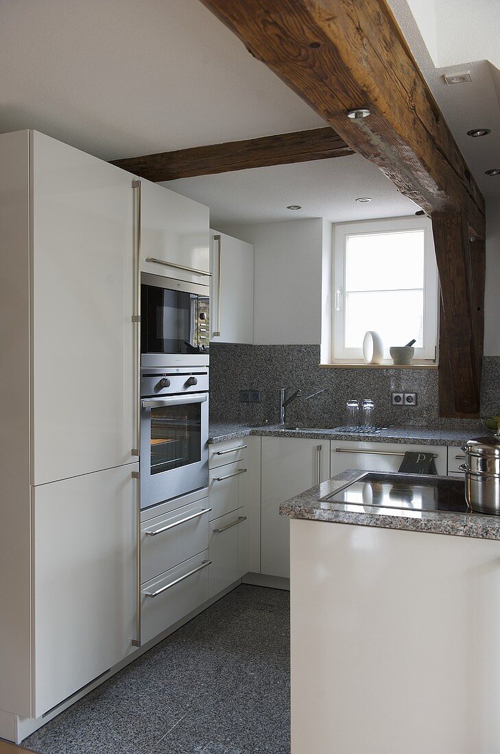 Moderne Küche mit weißen Schrankfronten, Arbeitsplatte und Boden aus Granit