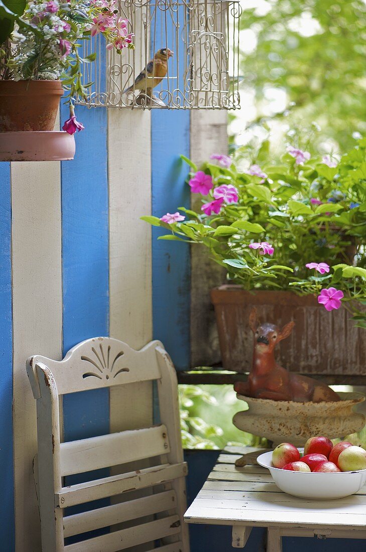 Balkon mit blau weiss gestreifter Holzwand und Blumen