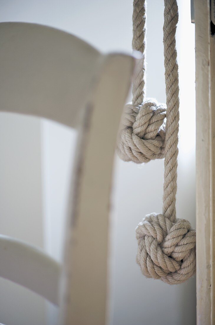 Zwei Seile mit Knotenende und Lehne eines Holzstuhls