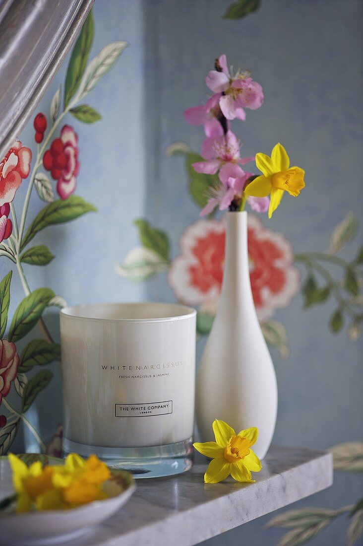 Blumen in weißer Vase und Windlicht auf Regal
