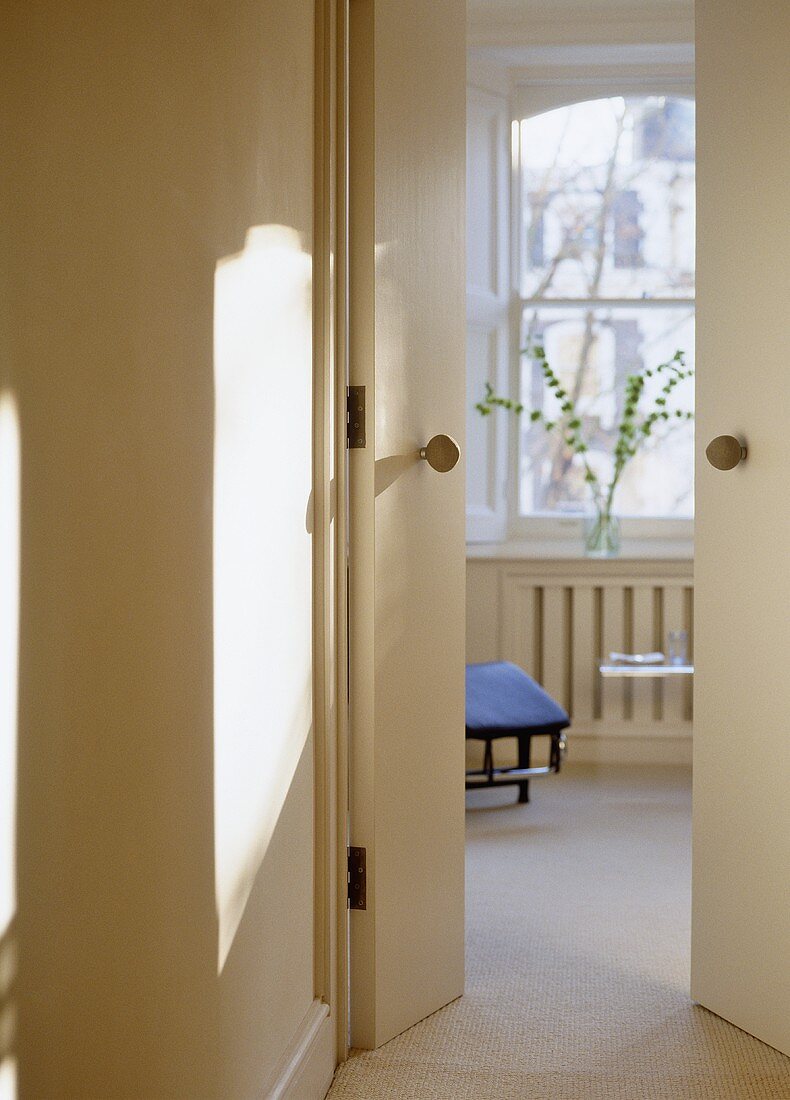 View through partly open doors into cream painted sitting room