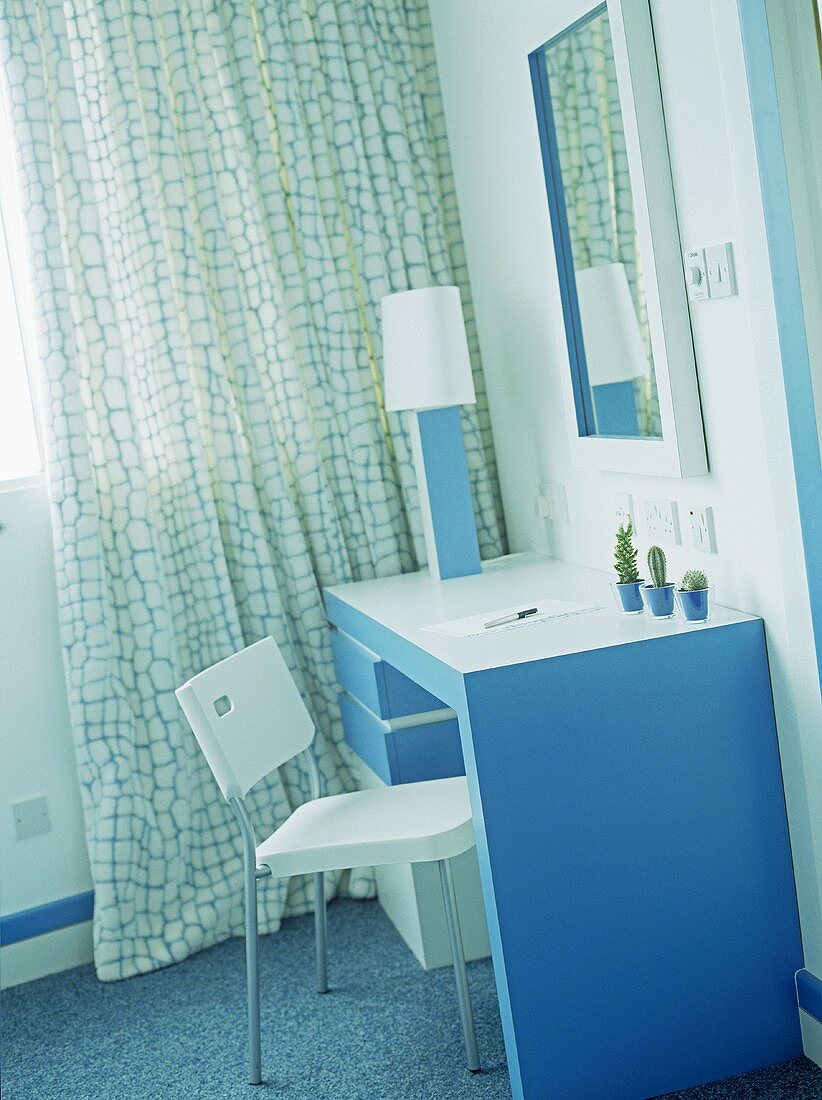 Hotel Schlafzimmer im Retro-Stil mit blau weißem Frisiertisch und Spiegel neben Vorhang am Fenster