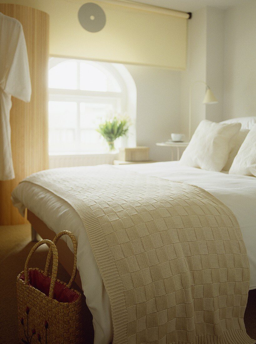 Double bed with woollen throw in white bedroom
