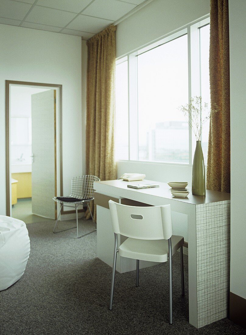 Hotel bedroom with retro styled dressing table and white plastic chair