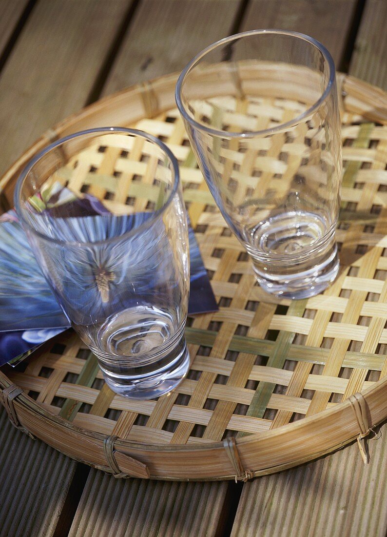 A detail of two glasses on a bamboo tray set on a wooden table,
