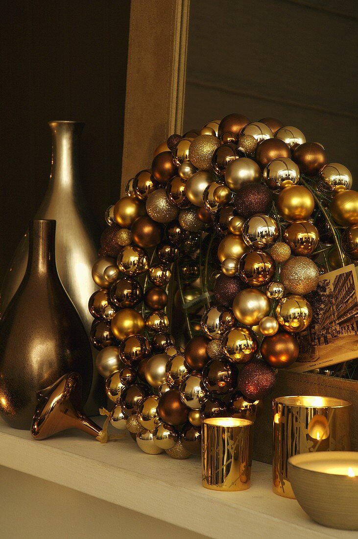 Kranz aus goldenen Weihnachtskugeln mit Windlichtern und Vasen in glänzenden Metallfarben