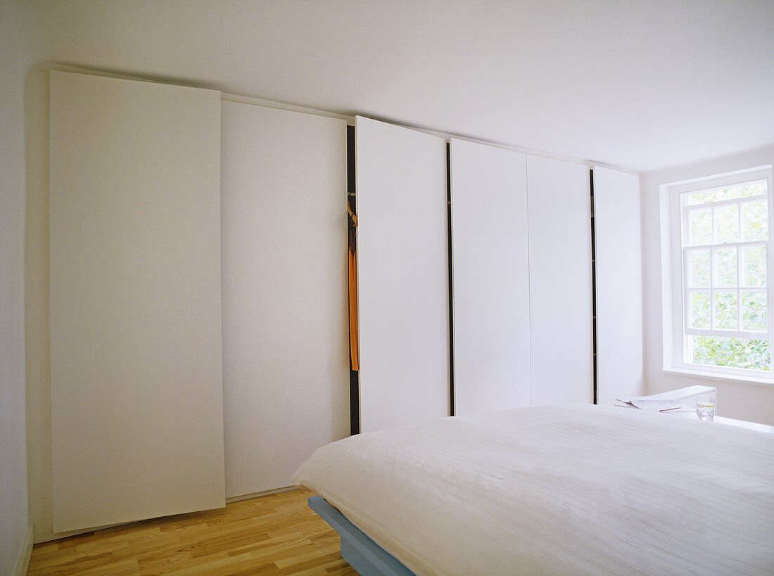Modernes weisses Schlafzimmer mit Einbauschrank neben Fenster