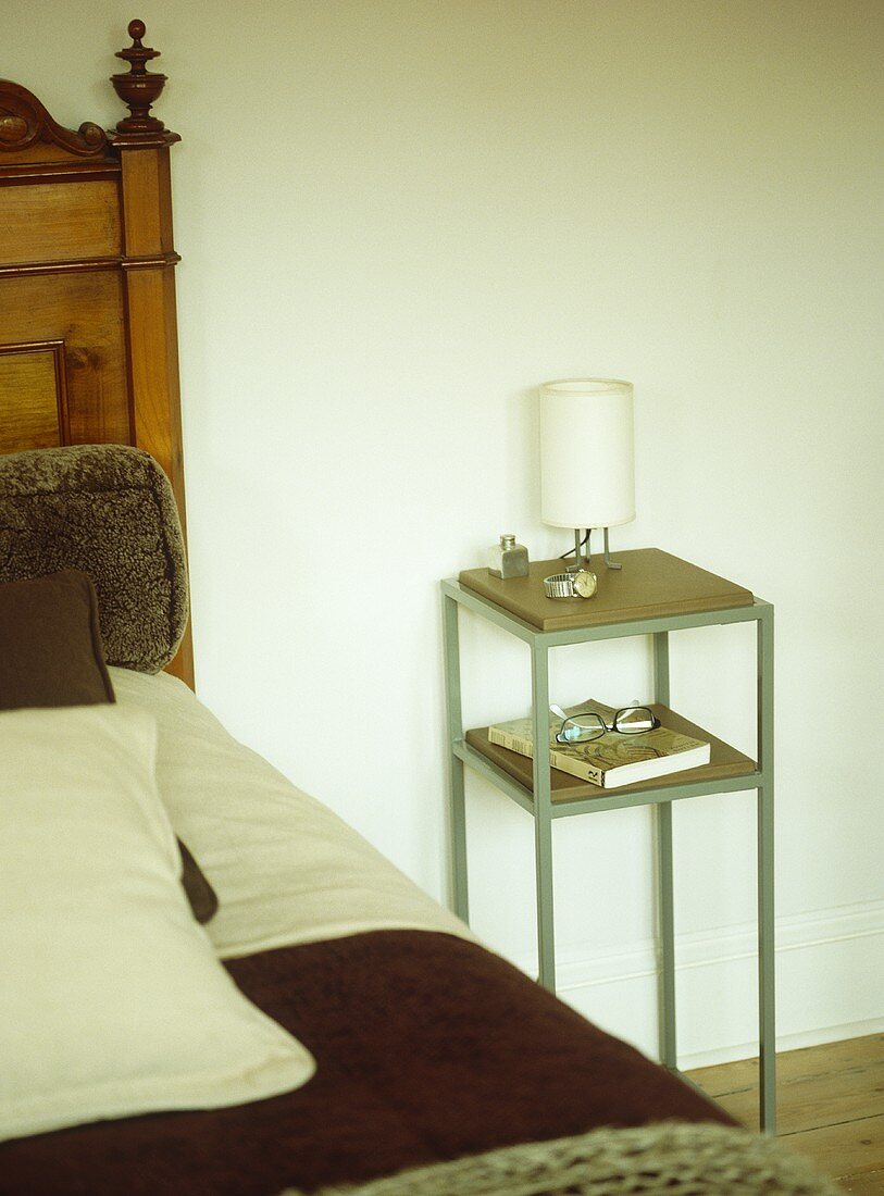 Moderner Nachttisch mit Lampe neben antikem Bett