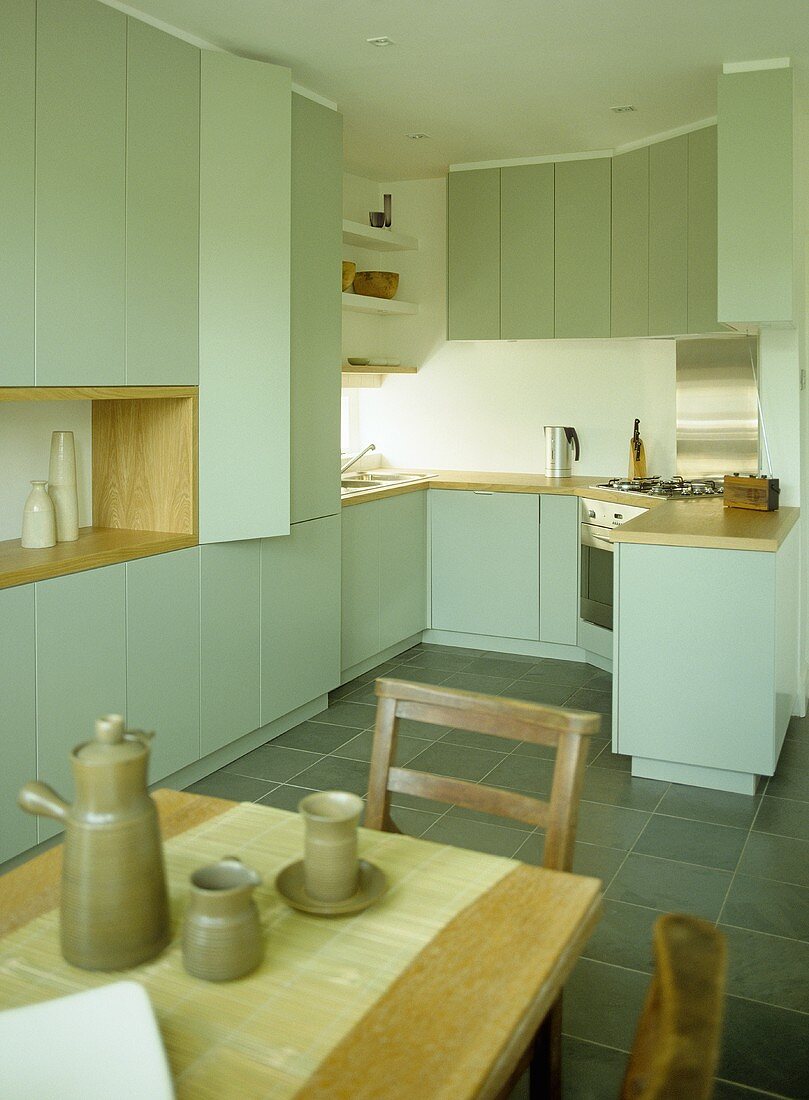 Dining table and chairs in kitchen with green fitted units