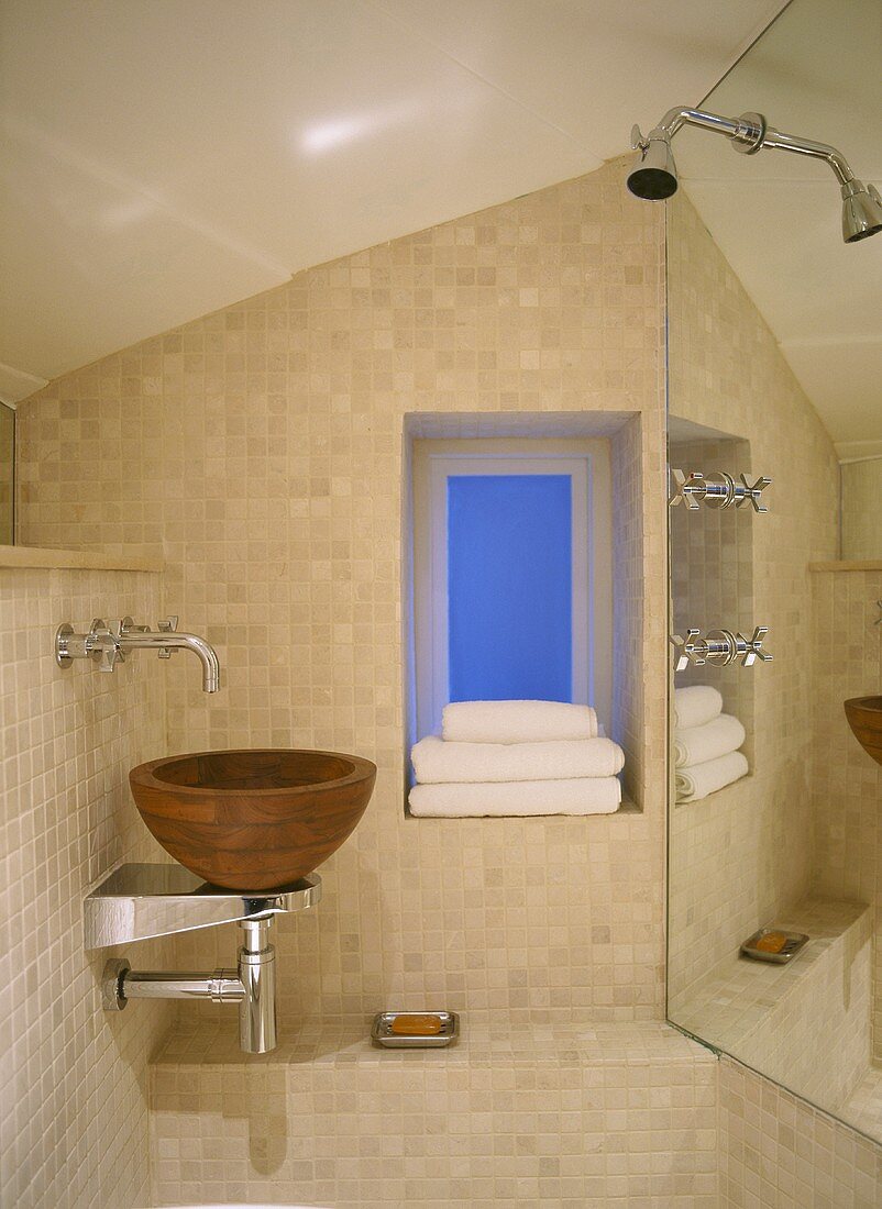 Waschschüssel aus Holz mit Wandarmatur und Dusche vor Wandspiegel im modernen Bad unter Dach