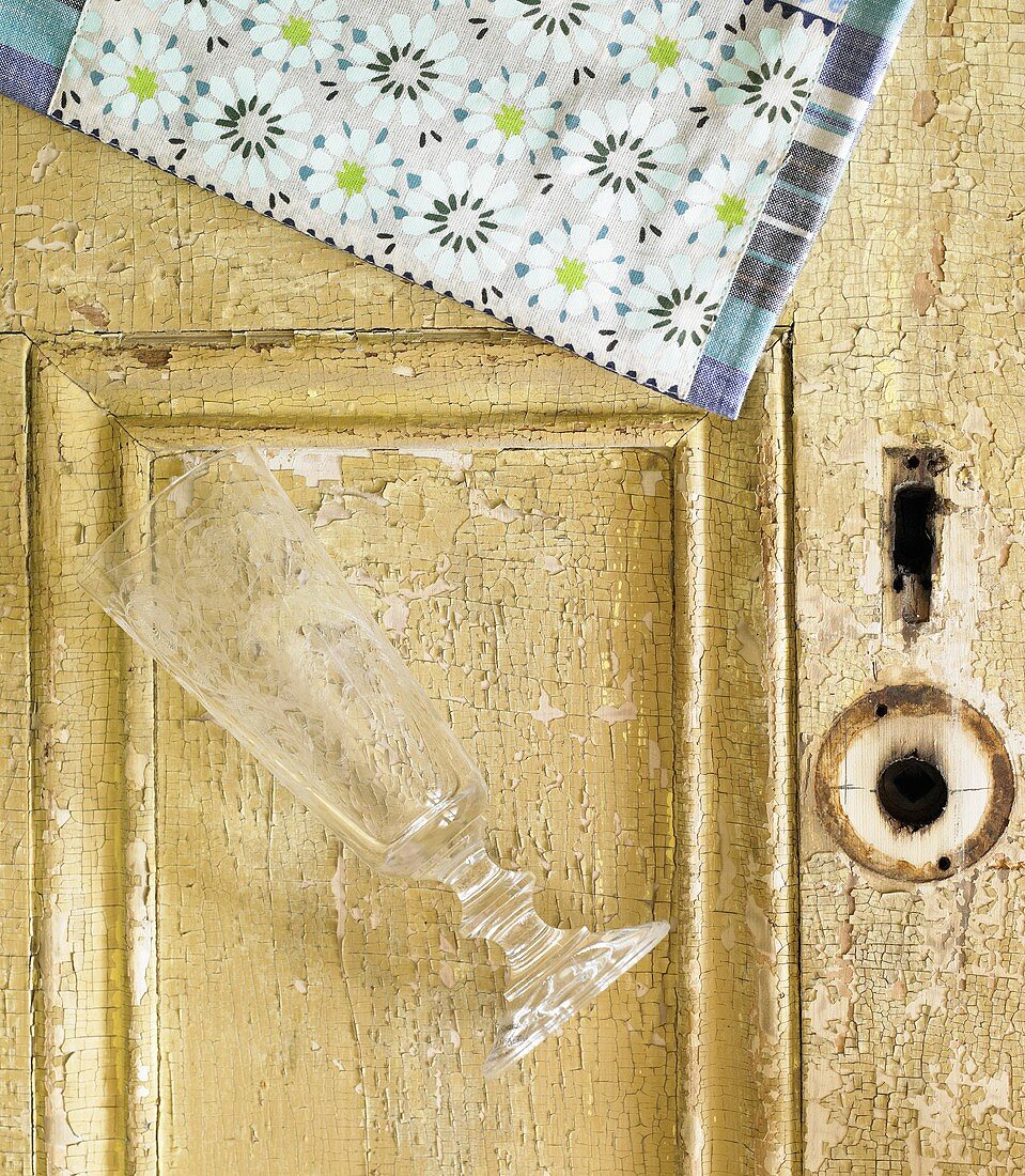 Leeres Sektglas & Serviette auf alter Tür liegend