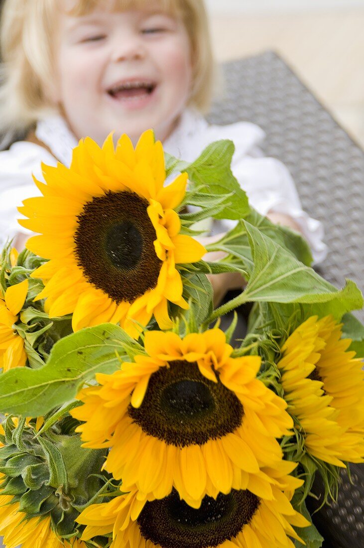 Little girl in traditional costume holding a bouquet of sunflowers