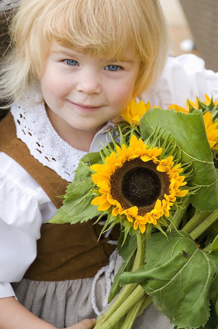 Little girl in traditional costume holding a bouquet of sunflowers