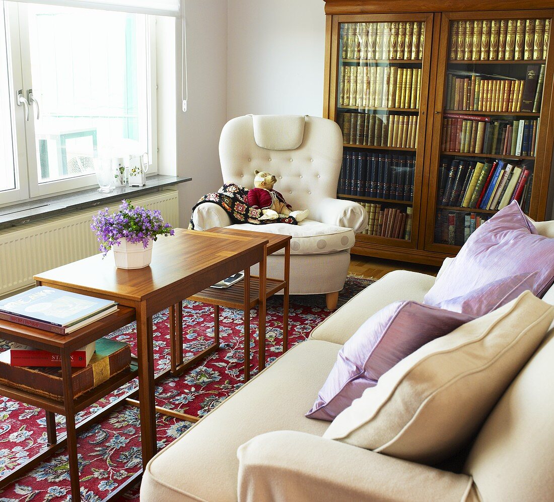 Ein Sofa, ein Sessel und ein antiker Bücherschrank in einem Wohnzimmer