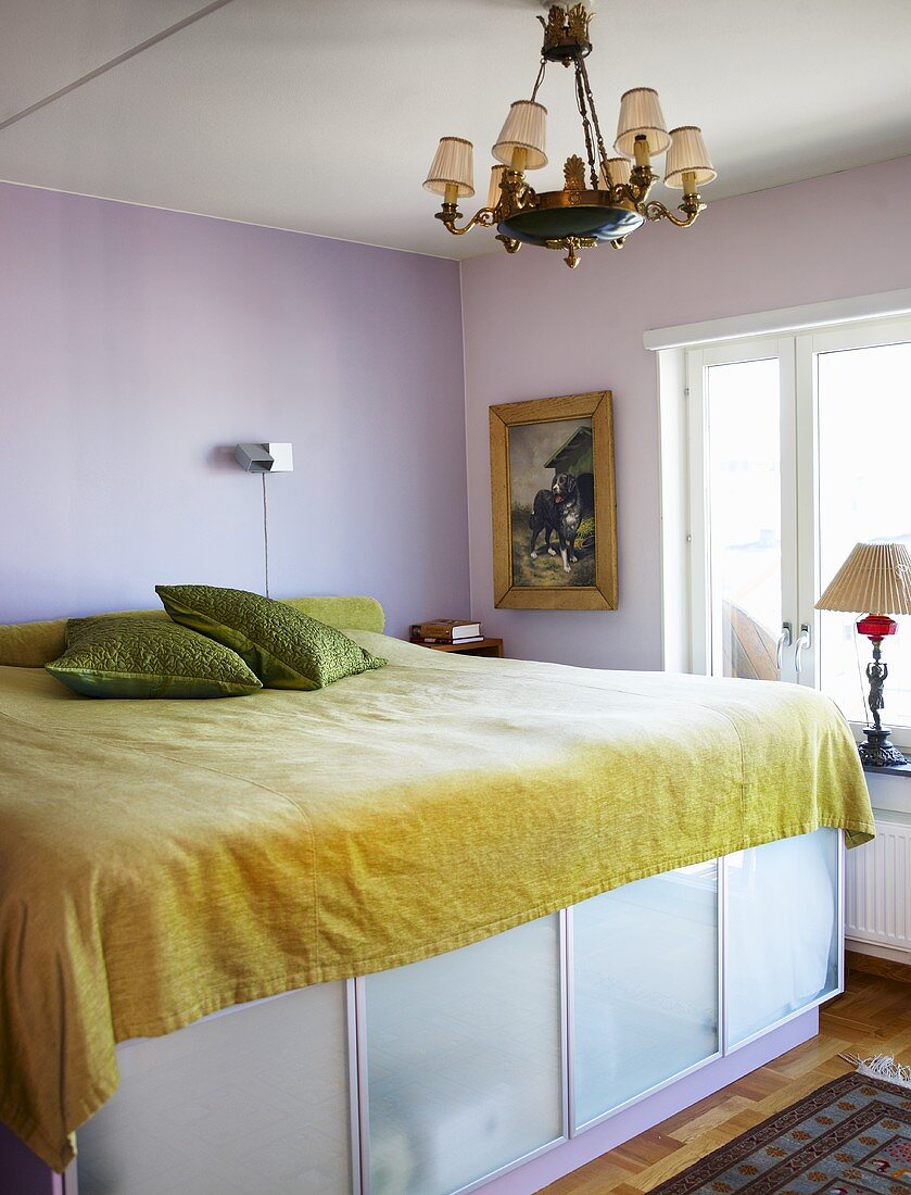 Ein Doppelbett, darunter Bettkasten mit Milchglasfronten in einem einfachen Schlafzimmer