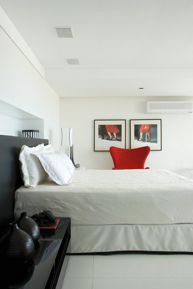 A black bedside table and a black headboard in a white bedroom