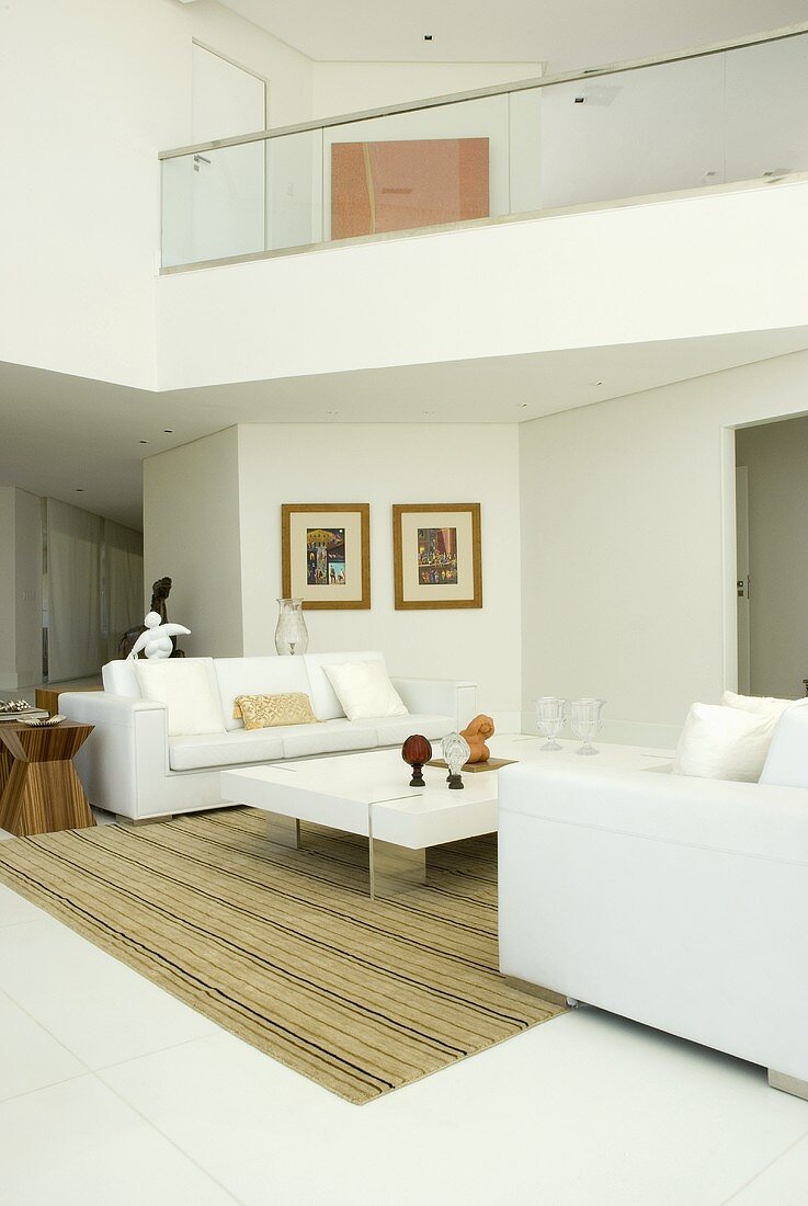 A view of a mezzanine floor from a living room with two white sofas and a coffee table