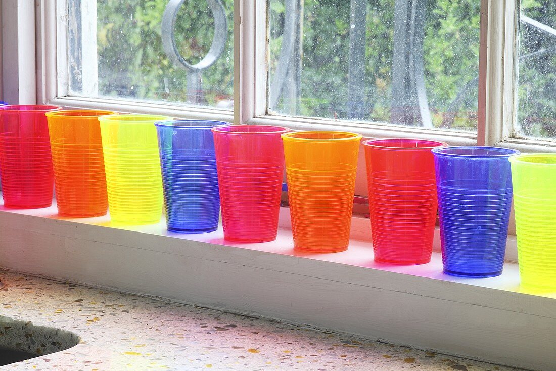 Colourful plastic cups on a window sill