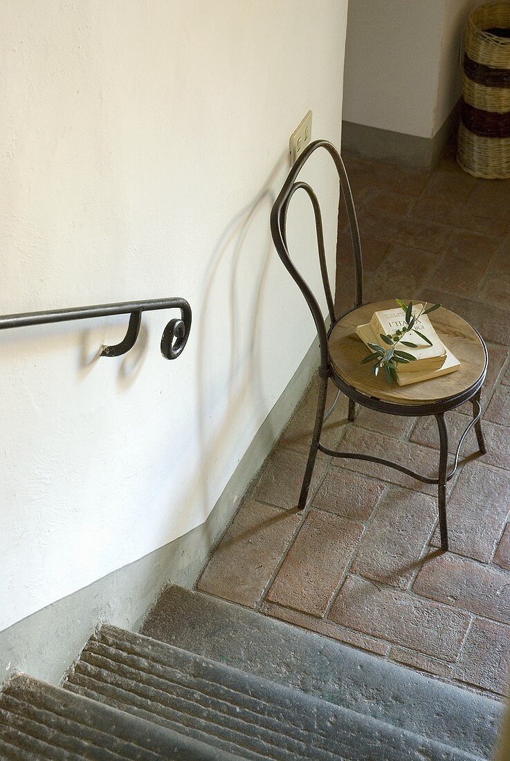 Ein Stuhl neben der Treppe in einer Diele mit Terrakottaboden