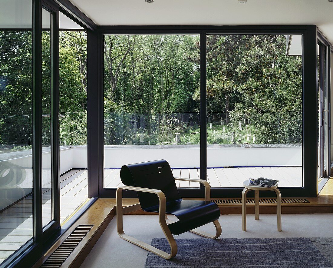 Sessel mit schwarz lackierter geschwungener Sitzfläche aus Bauhauszeit vor Terrassenfenster