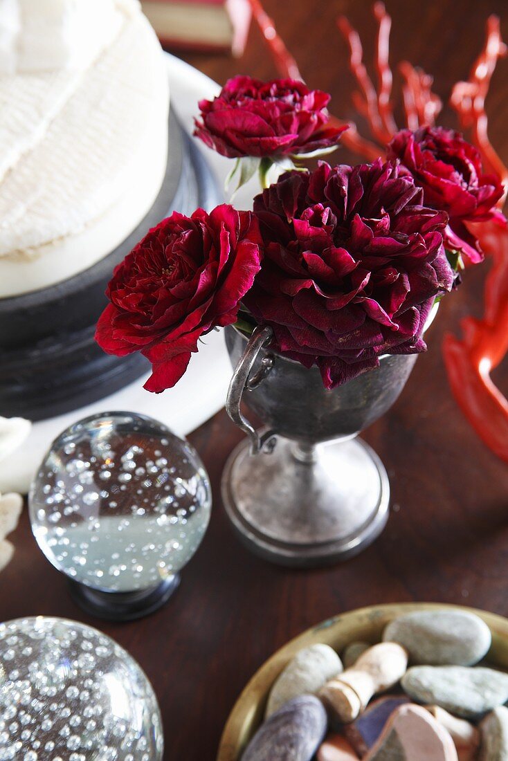 Rote Rosen, Steine und Schneekugel als Tischdekoration