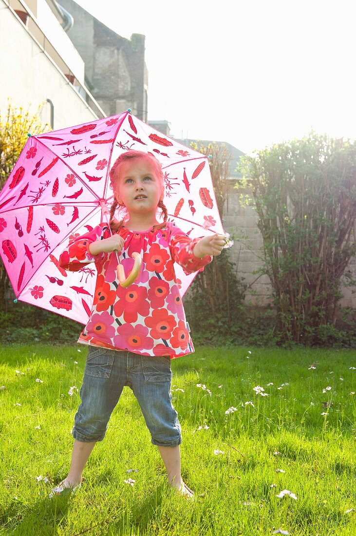 Kleines Mädchen mit Schirm im Garten